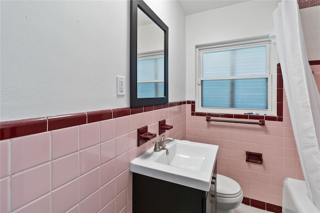 bathroom featuring toilet, vanity, and tile walls