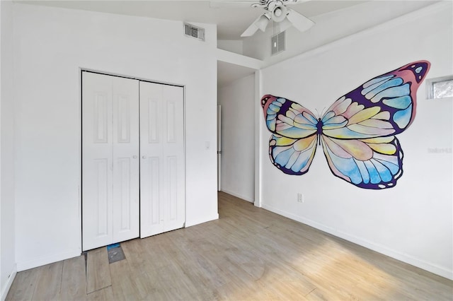 unfurnished bedroom with ceiling fan, a closet, light wood-type flooring, and lofted ceiling