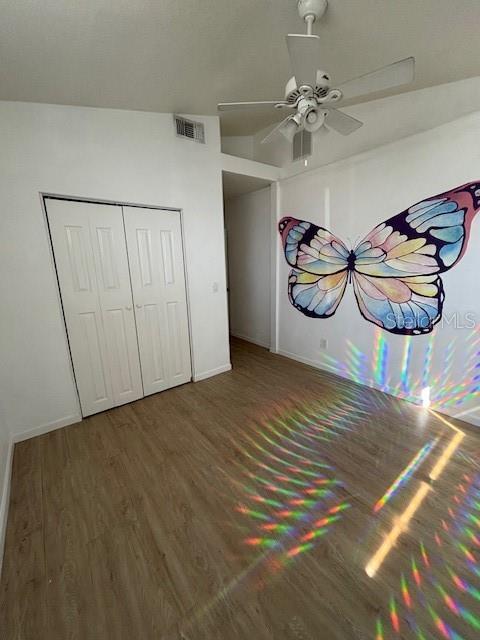 unfurnished bedroom featuring dark wood-type flooring, ceiling fan, and a closet