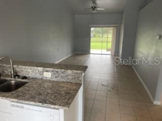 kitchen featuring white cabinets, light tile patterned floors, sink, ceiling fan, and light stone countertops