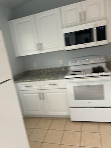 kitchen with white appliances, white cabinetry, and light tile patterned floors