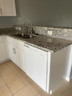 kitchen featuring white cabinetry, dark stone counters, sink, and light tile patterned floors