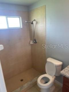 bathroom featuring toilet, vanity, and tiled shower