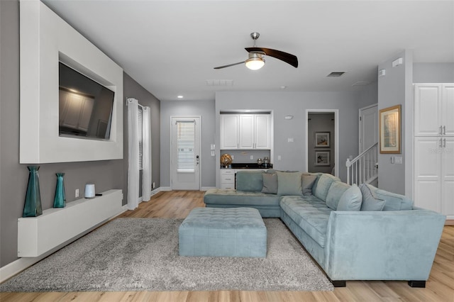 living room with light hardwood / wood-style flooring and ceiling fan