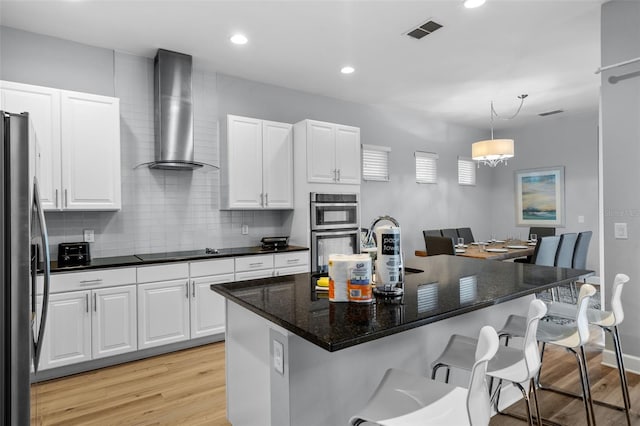 kitchen with white cabinetry, stainless steel appliances, and wall chimney range hood