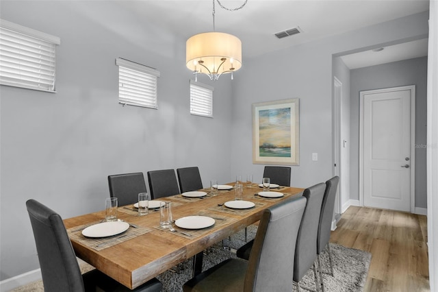 dining space with light wood-type flooring and an inviting chandelier