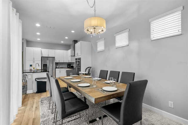 dining space with light hardwood / wood-style flooring, an inviting chandelier, and sink