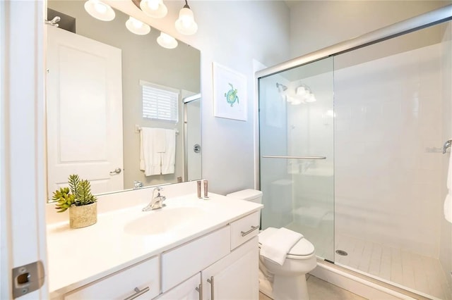 bathroom with vanity, toilet, and a shower with door