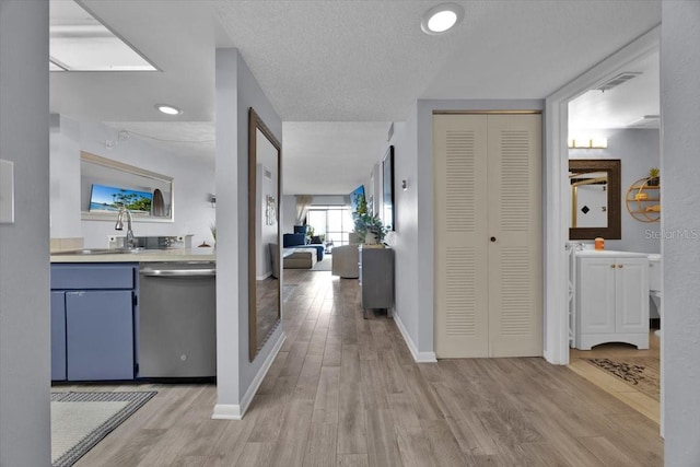 hall featuring sink, a textured ceiling, and light wood-type flooring