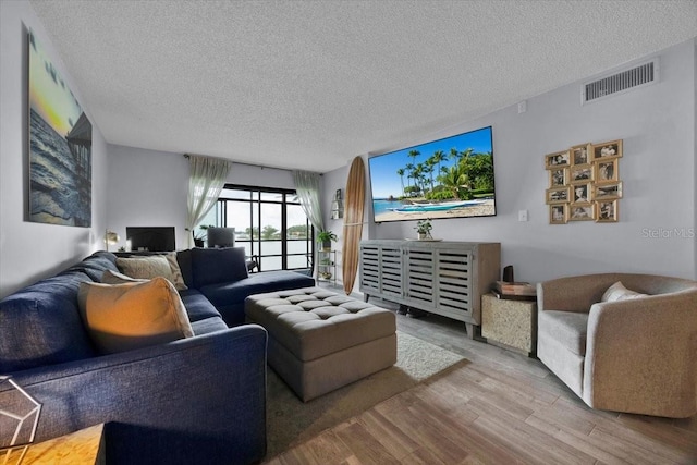 living room with a textured ceiling and light hardwood / wood-style floors