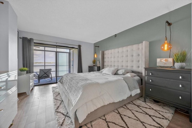 bedroom featuring lofted ceiling, hardwood / wood-style flooring, access to outside, and a textured ceiling