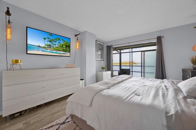 bedroom featuring hardwood / wood-style flooring, access to outside, and a textured ceiling