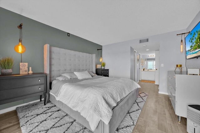 bedroom with ensuite bath and light wood-type flooring