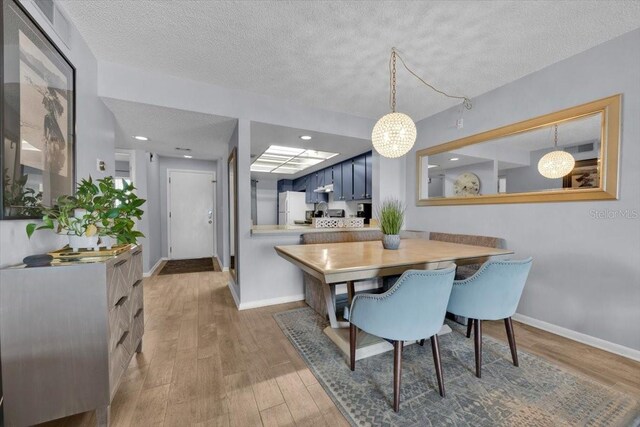 dining room with an inviting chandelier, wood-type flooring, and a textured ceiling