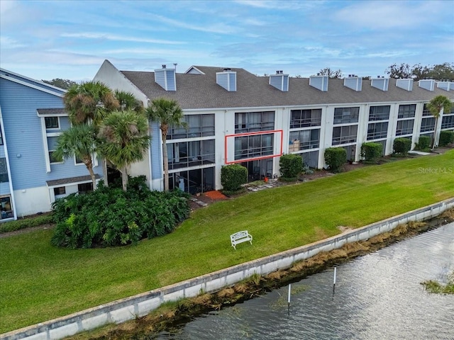 back of house featuring a lawn and a water view