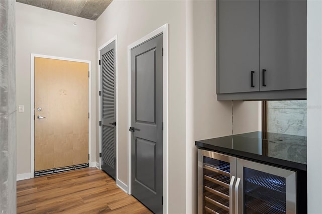 bar with gray cabinets, light hardwood / wood-style floors, and beverage cooler