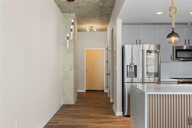 kitchen featuring decorative backsplash, stainless steel appliances, wood-type flooring, and decorative light fixtures