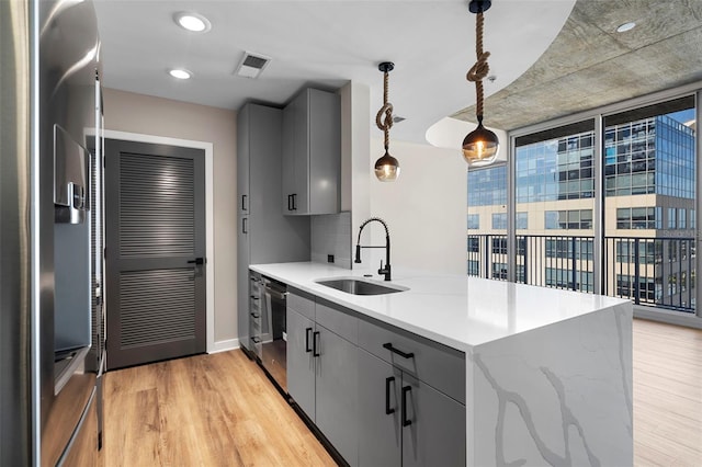 kitchen featuring light hardwood / wood-style floors, sink, decorative light fixtures, and gray cabinetry