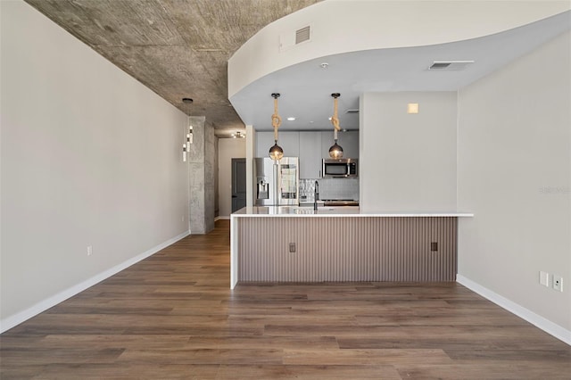 kitchen with stainless steel appliances, kitchen peninsula, hanging light fixtures, a breakfast bar area, and dark hardwood / wood-style floors