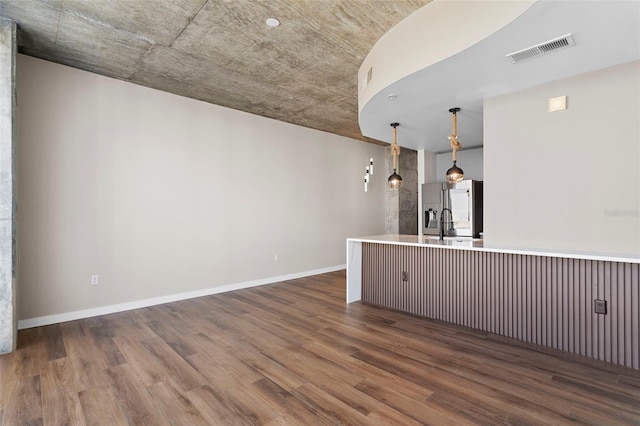 bar with hanging light fixtures, stainless steel fridge, and dark hardwood / wood-style floors