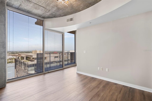 unfurnished room featuring expansive windows, wood-type flooring, and a healthy amount of sunlight