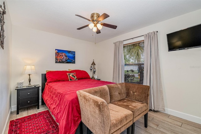 bedroom with ceiling fan, light hardwood / wood-style flooring, and a textured ceiling