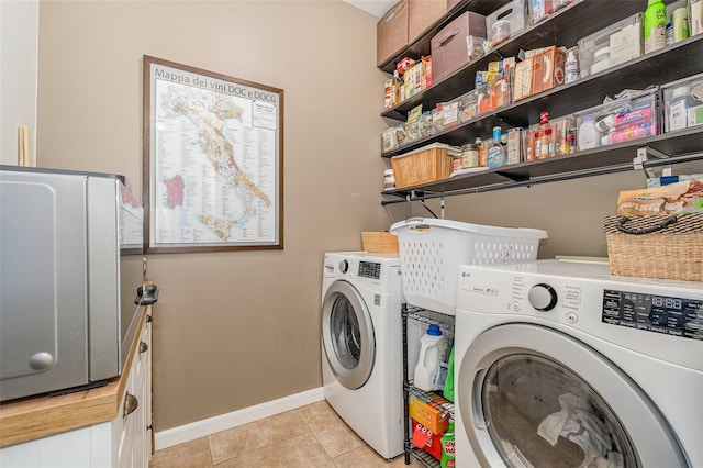 clothes washing area with washing machine and clothes dryer and light tile patterned floors