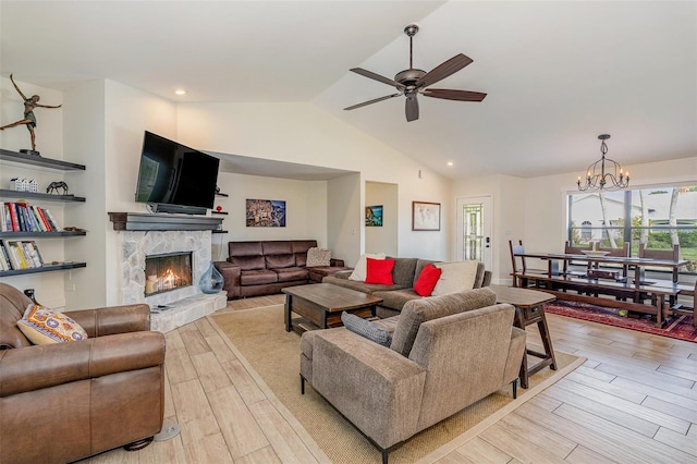 living room with a fireplace, ceiling fan with notable chandelier, lofted ceiling, and light wood-type flooring