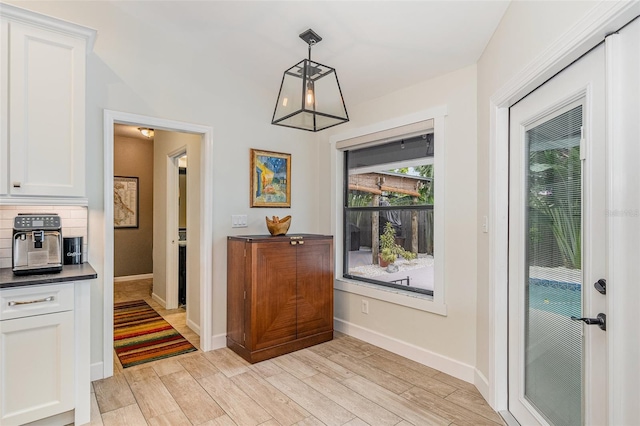 doorway to outside with light hardwood / wood-style floors and vaulted ceiling