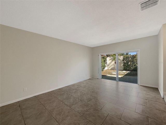 unfurnished room featuring a textured ceiling and dark tile patterned flooring