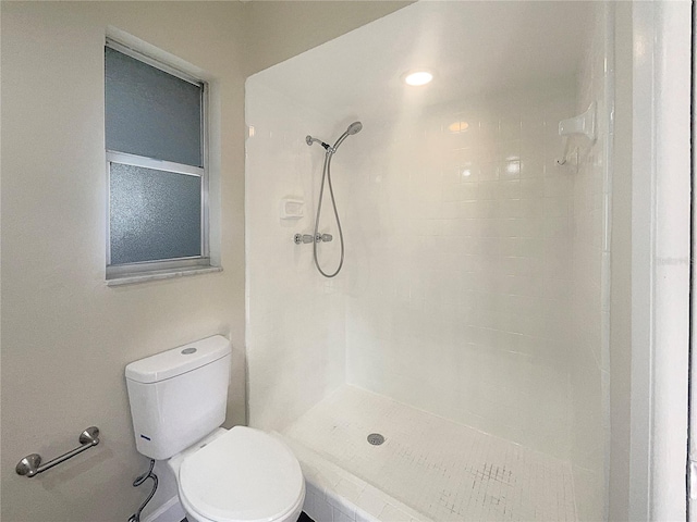 bathroom featuring tiled shower and toilet