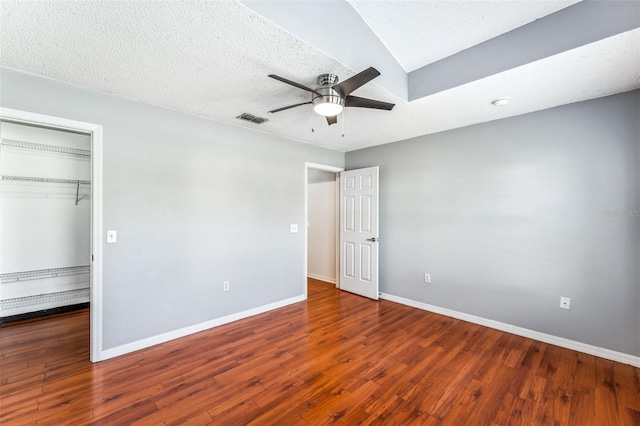 unfurnished bedroom with a textured ceiling, ceiling fan, a closet, and dark hardwood / wood-style floors