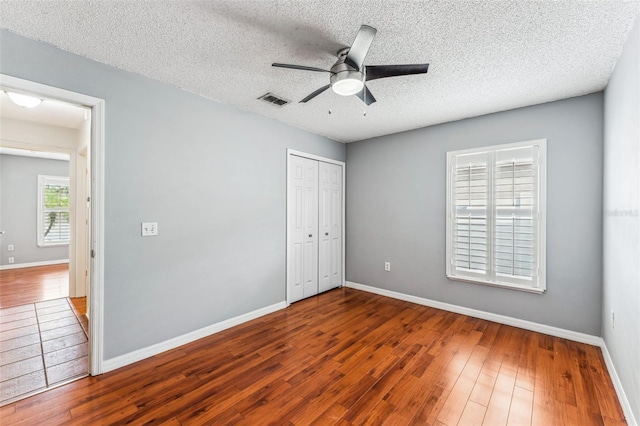 unfurnished bedroom featuring hardwood / wood-style floors, ceiling fan, and a textured ceiling