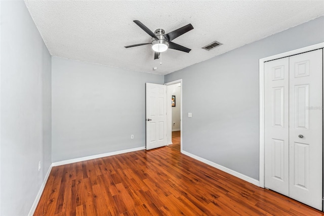 unfurnished bedroom featuring wood-type flooring, a textured ceiling, and ceiling fan