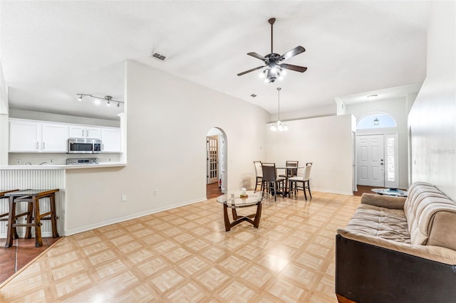 living room with light parquet floors, track lighting, and ceiling fan with notable chandelier