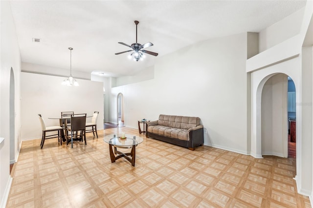 living room with a textured ceiling, ceiling fan with notable chandelier, light parquet floors, and vaulted ceiling