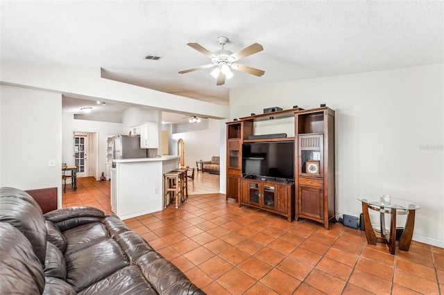 tiled living room with a textured ceiling and ceiling fan