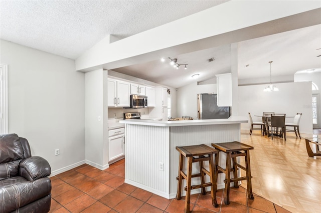 kitchen with pendant lighting, white cabinets, stainless steel appliances, and lofted ceiling