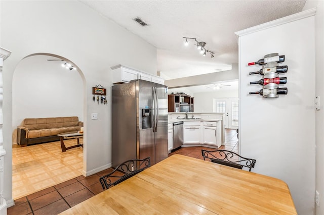 kitchen featuring tile patterned floors, a textured ceiling, stainless steel appliances, sink, and white cabinetry