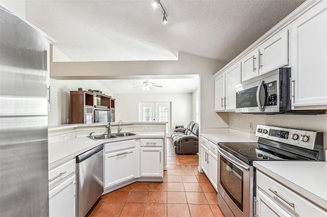 kitchen with sink, white cabinets, vaulted ceiling, and appliances with stainless steel finishes