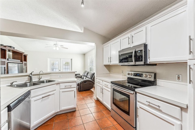 kitchen featuring appliances with stainless steel finishes, white cabinetry, lofted ceiling, and sink