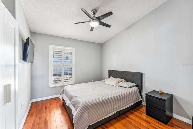 bedroom featuring ceiling fan, wood-type flooring, and a textured ceiling