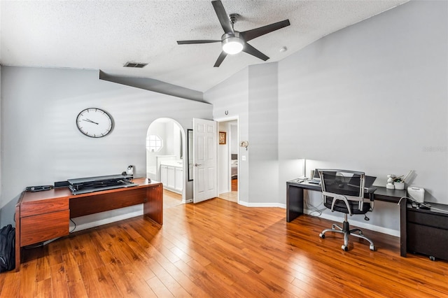 home office featuring ceiling fan, light hardwood / wood-style floors, a textured ceiling, and high vaulted ceiling