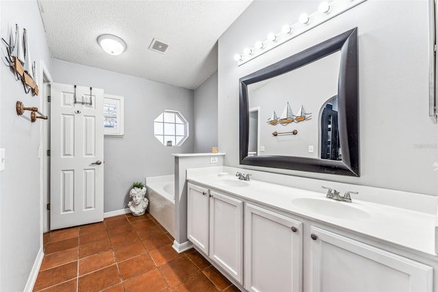 bathroom with tile patterned floors, vanity, a textured ceiling, and tiled tub