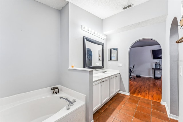 bathroom featuring a washtub, vanity, a textured ceiling, and tile patterned floors