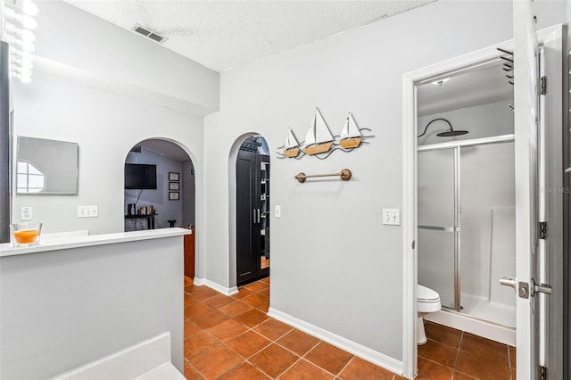 bathroom with tile patterned flooring, toilet, and a shower with door