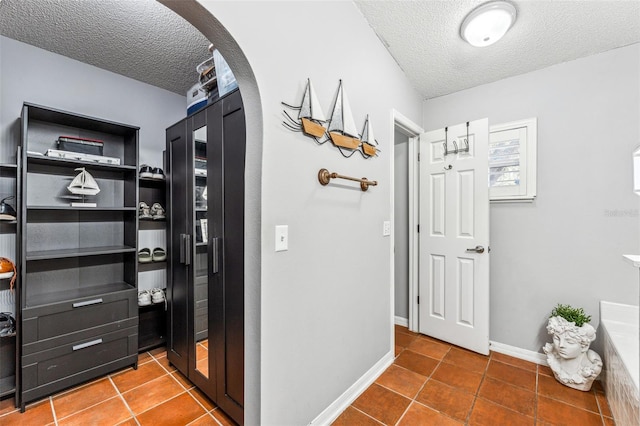 corridor featuring tile patterned flooring and a textured ceiling