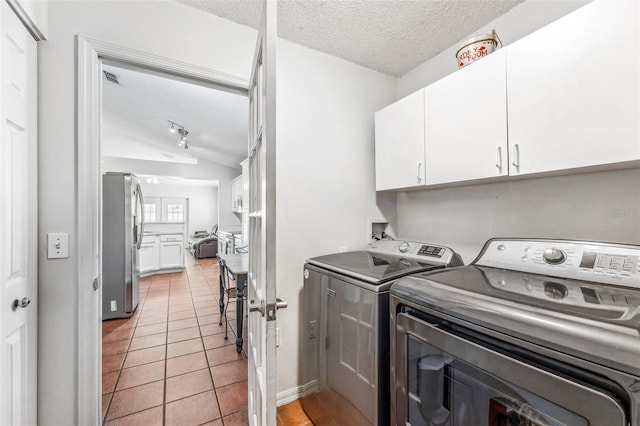 clothes washing area with light tile patterned floors, cabinets, a textured ceiling, and independent washer and dryer