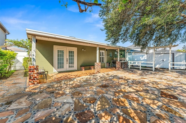 rear view of property with french doors, a patio, and a storage shed