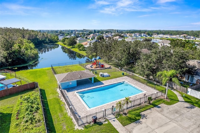 view of swimming pool featuring a playground, a water view, and a lawn